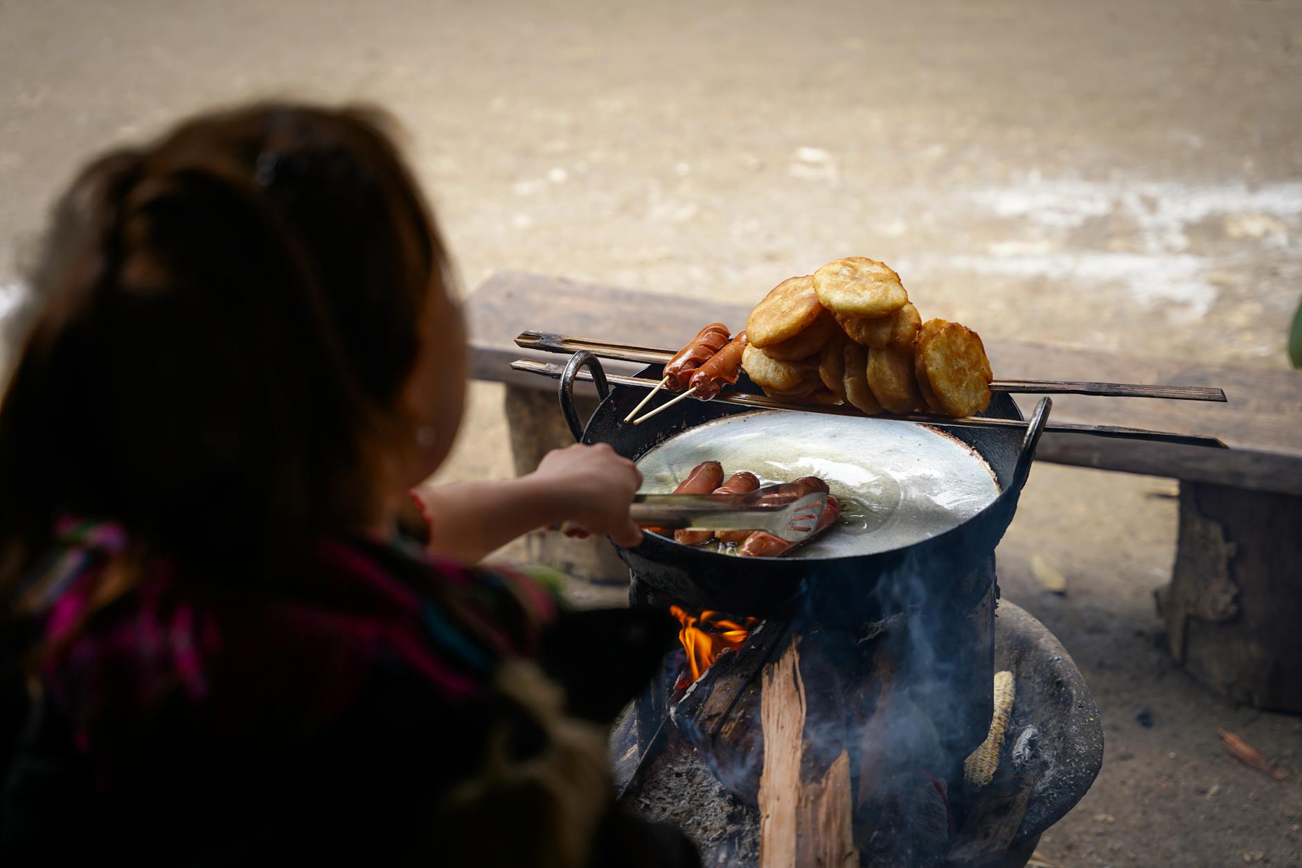 A person cooking traditional Vietnamese street food on an outdoor stove in Mộc Châu, Vietnam.