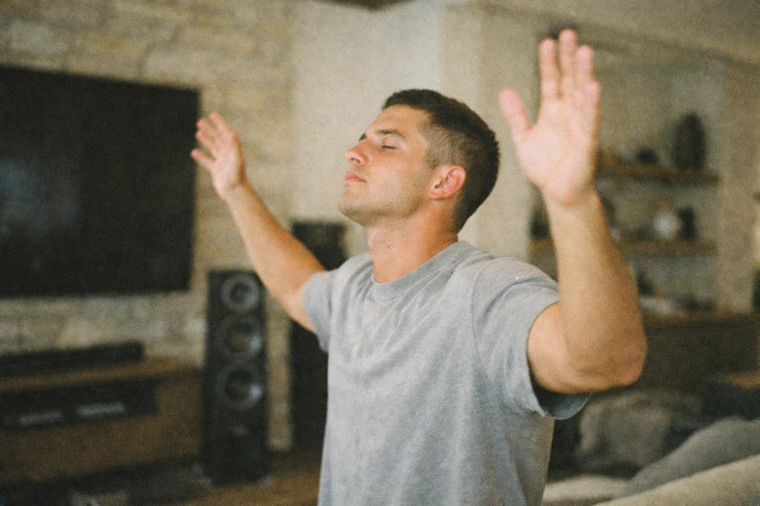 A man with arms lifted in worship, eyes closed
