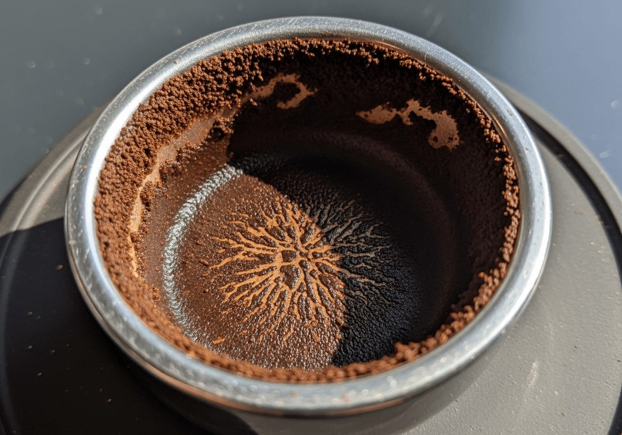 Nahaufnahme eines Espresso-Pucks, der Anzeichen von Channeling mit ungleichmäßigen Extraktionsspuren zeigt