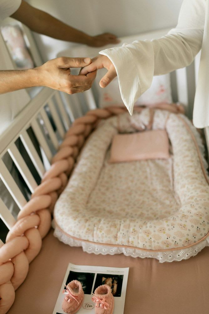 Modernes Thermometer und Nachtlicht auf einem Nachttisch neben einem leeren Beistellbett zur Überwachung bei Baby-Notfällen. | Foto: Alexander Mass