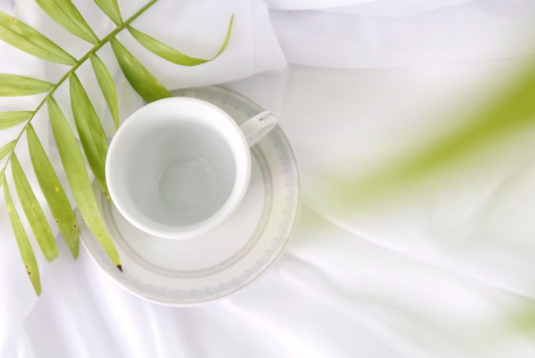 Flatlay einer weißen Espressotasse neben einer Zahnbürste und Wasser als Symbol für Kaffee und Zähne ohne Verfärbungen.