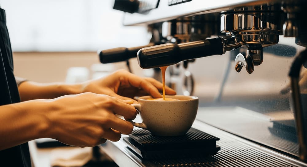 Das optimale Brühverhältnis finden: Barista brüht Espresso auf einer digitalen Waage unter der Maschine im warmen Café.