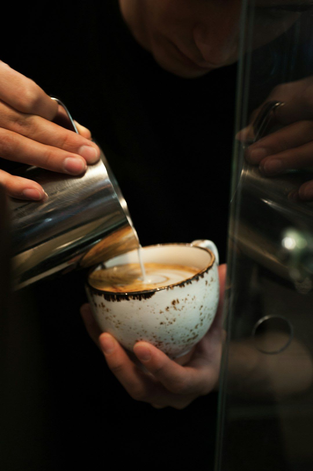 Eine Hand siebt feinen Kakao über die Creme einer Cappuccino Torte und vollendet so die Dekoration für den perfekten Kaffeegenuss. | Foto: David Foodphototasty