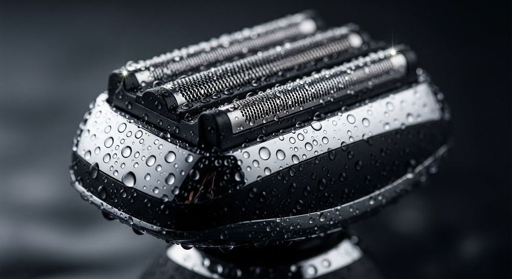 Nahaufnahme des Scherkopfs eines Braun Series 9 Pro mit Wassertropfen, die die deutsche Anleitung zur Reinigung illustriert.