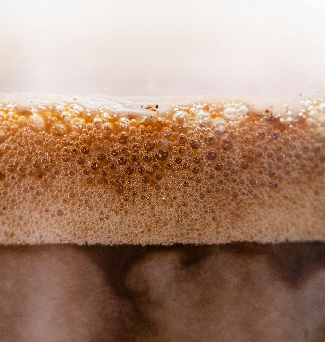 Ein erfrischender Eiskaffee mit Protein wird in einem hohen Glas umgerührt, garniert mit Schokoladensauce und Eiswürfeln. | Foto: Nature Zen