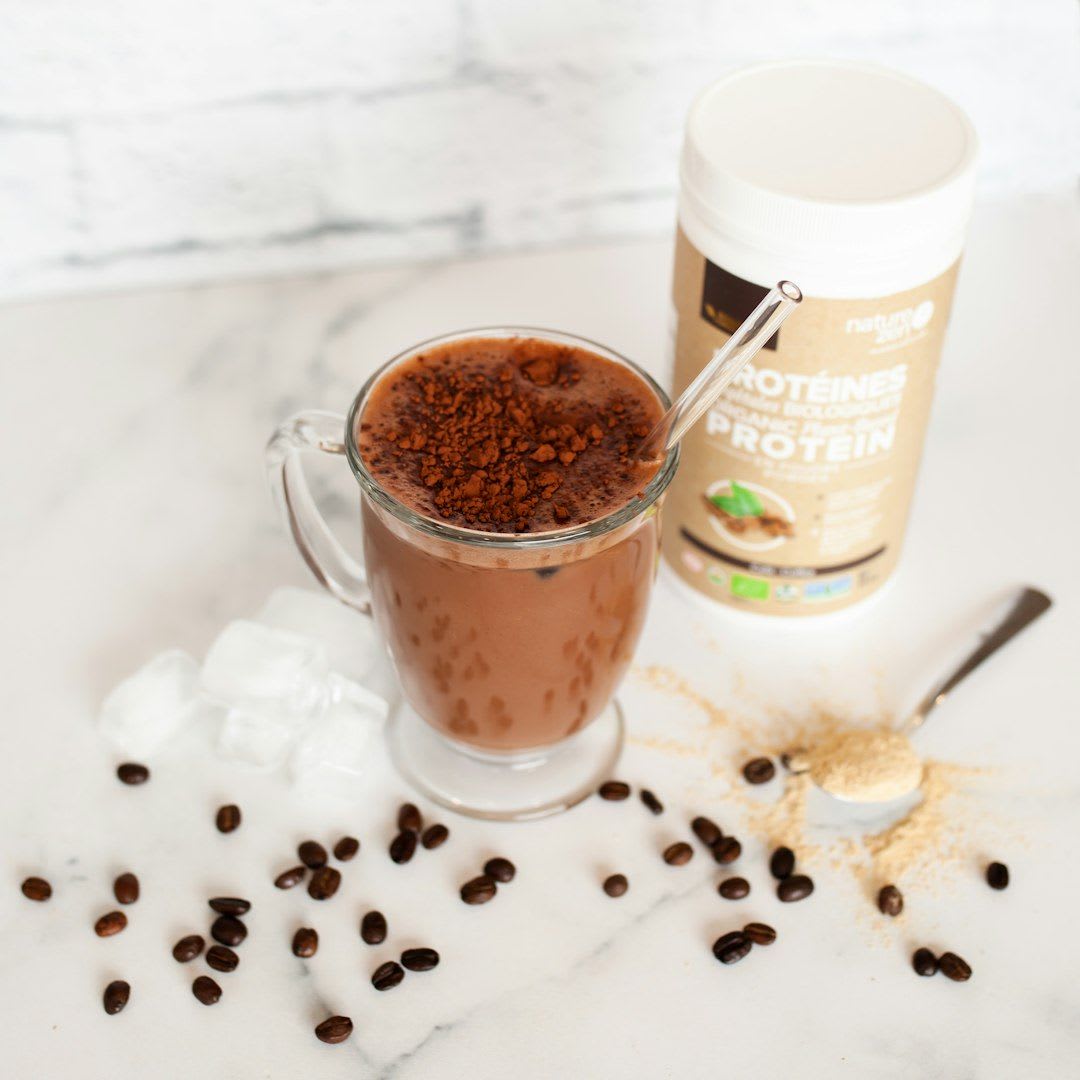 Zutaten für Kaffee mit Protein: Eine Dose mit geschmacksneutralem Proteinpulver neben einem Glas mit frischem Espresso. | Foto: Nature Zen