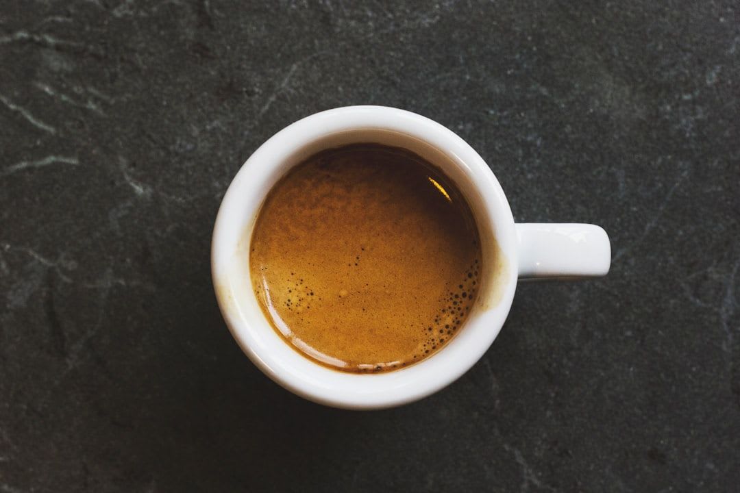 Eine Hand gießt Milch in eine Tasse Kaffee, ein Symbol für die zusätzlichen Kalorien im Kaffee und den bewussten Genuss. | Foto: Matt Hoffman