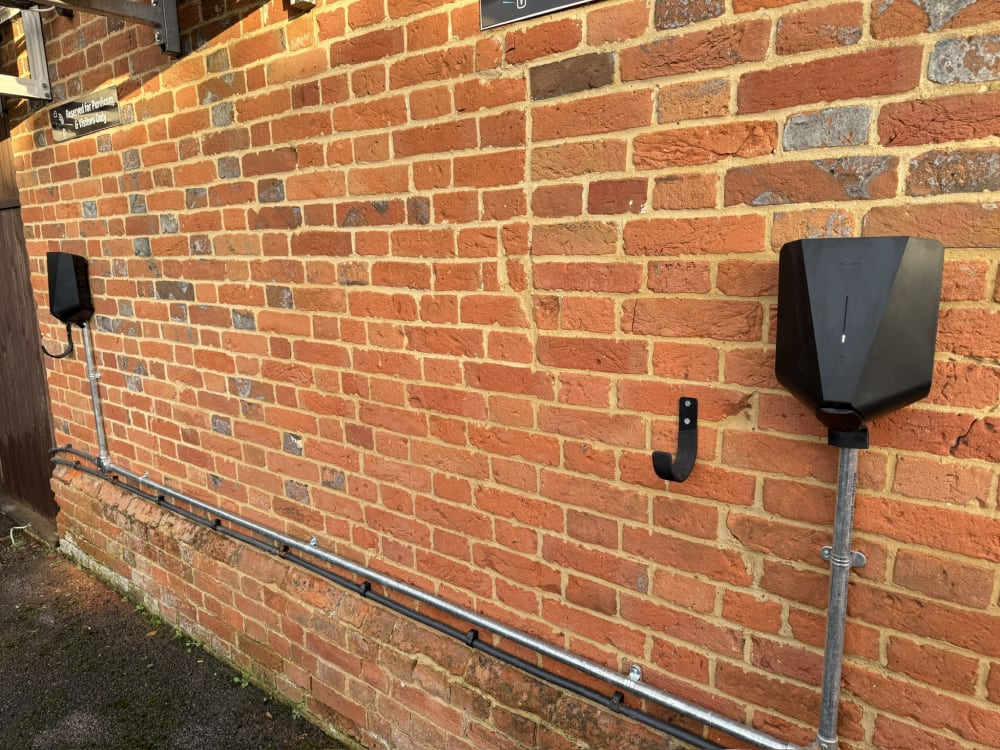 Two low-profile Easee chargers on heritage brickwork with galvanised conduit drops at Purdicom, Wantage.