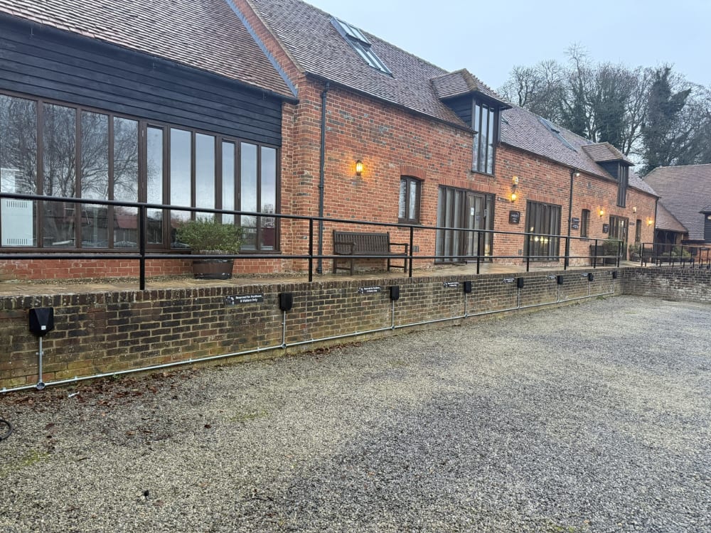 Row of Easee chargers with galvanised conduit along the heritage barn wall at Purdicom, Wantage, Oxfordshire.