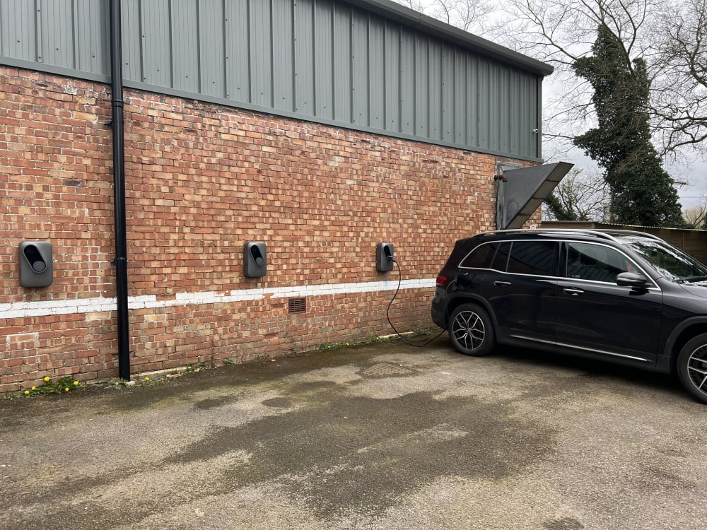 Three Landis+Gyr chargers on the warehouse wall with an electric Mercedes charging at Route One, Acton Turville.