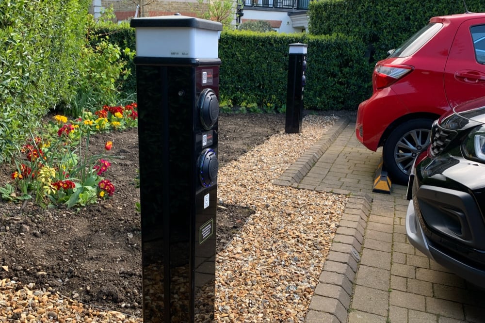 Two Rolec dual bollard EV chargers installed beside colourful flower beds and shingle landscaping at Ashby Lodge, Hendon.