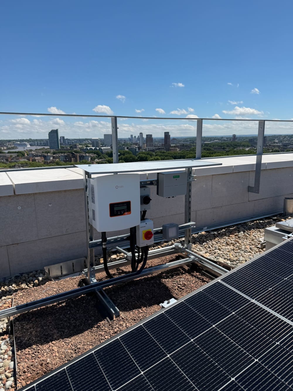 Solis solar inverter on a green-roof mounting frame in Canada Water, London, with the Canary Wharf skyline behind.