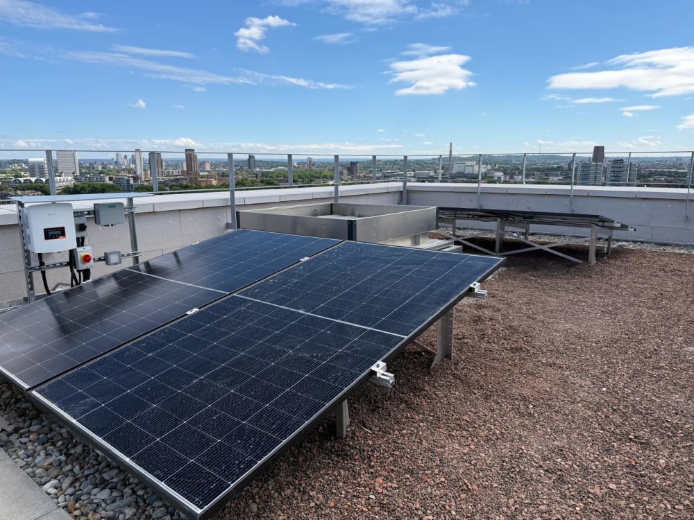 Close view of green-roof solar panels in Canada Water, London, with The Shard and the City skyline beyond.