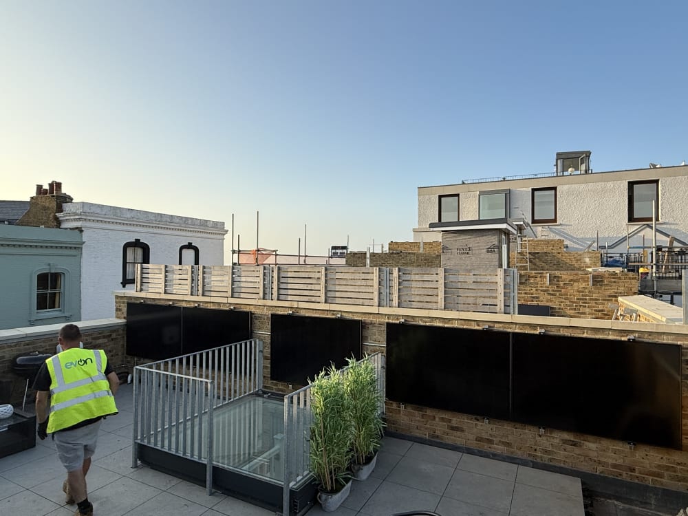 EV-ON engineer in branded hi-vis on the show home rooftop terrace at Fort Mount, Margate, Kent, during the wall-mounted solar PV install.