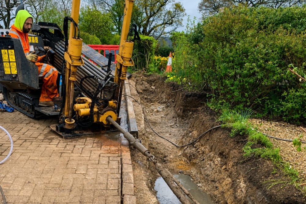 Operator running horizontal directional drilling rig to install underground cable ducts at Berkhamsted hospice grounds.