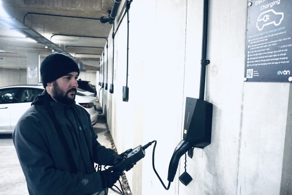 An evon engineer running maintenance tests on a wall mounted Easee EV charger in the underground car park at Millbrook Park, Mill Hill.