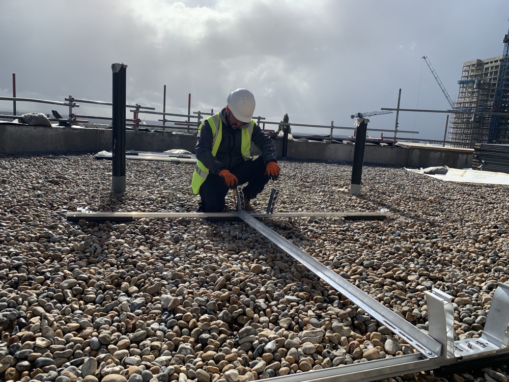 EV-ON engineer installing K2 D-Dome Xpress solar mounting rail on the Level 6 flat roof at The Mirador, Acton.