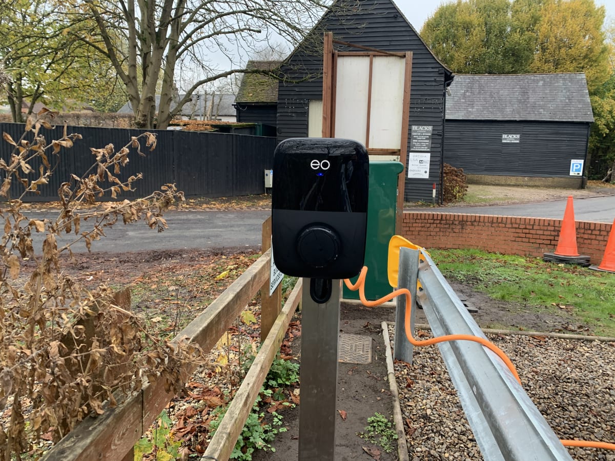 An EO Genius 2 22kW charger mounted on a metal pedestal post with orange cable in Hollywell's car park in St Albans.