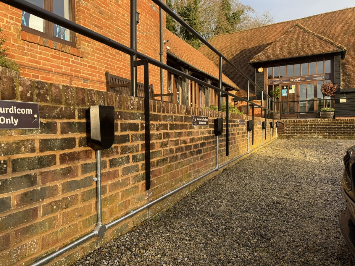 Multiple Easee 22kW chargers mounted on brick wall with galvanised conduit at Purdicom car park, Wantage.