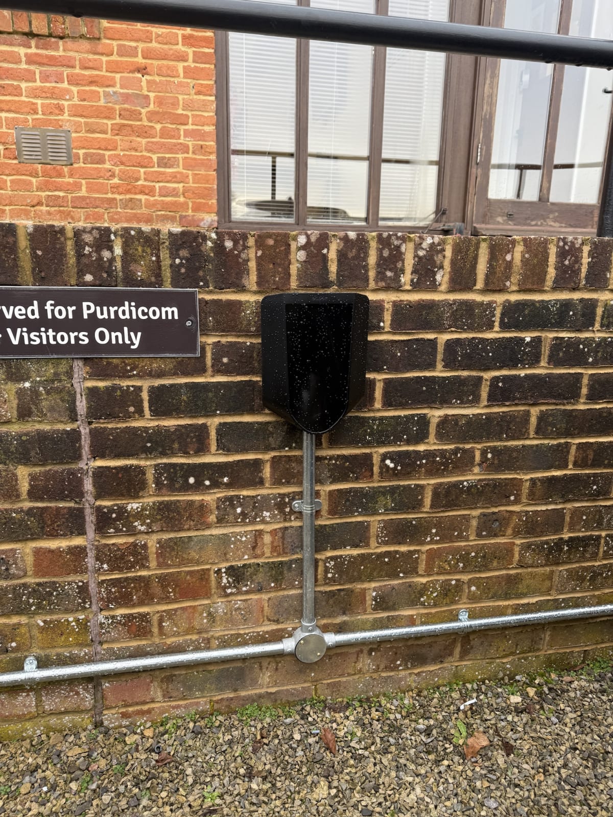 Easee charger above a reserved visitor parking sign with galvanised conduit drop at Purdicom, Wantage.
