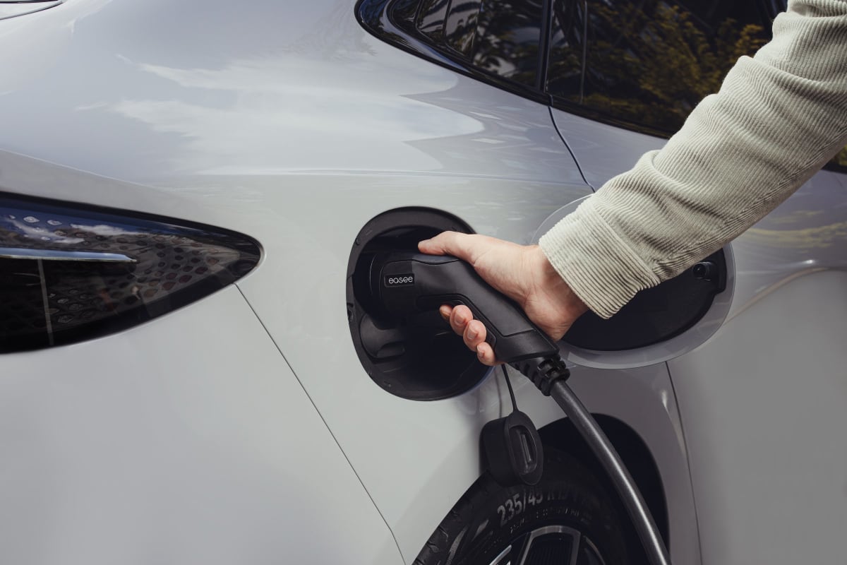 An Easee EV charger being plugged into a white car
