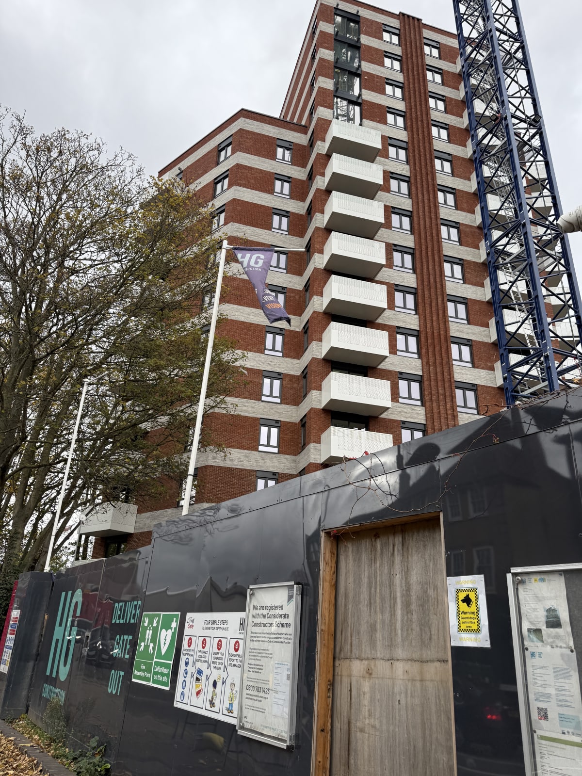 Exterior view of Brooke House, a 15-storey new build apartment tower on Gunnersbury Lane in Acton, London, with HG Construction hoarding.