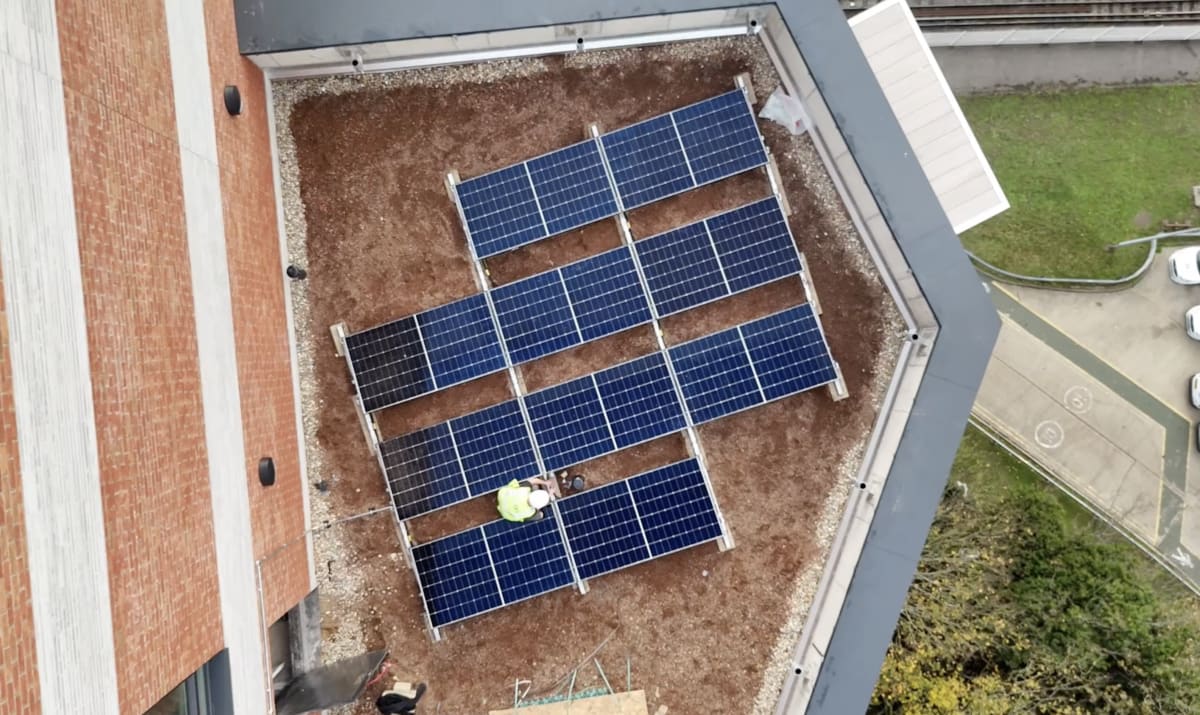 Aerial drone view of near-complete 10-panel Longi solar array on the 13th floor roof at Brooke House, Acton, London.