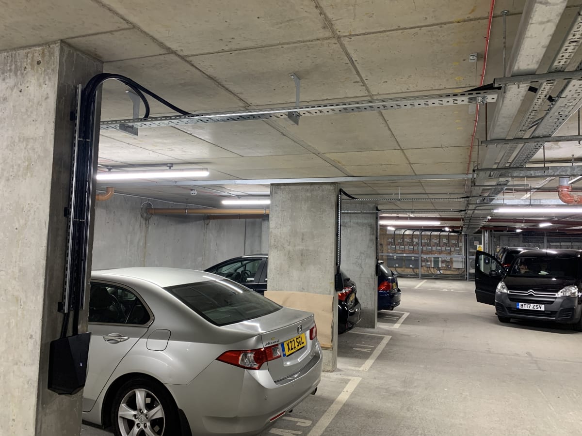 Underground car park at Denver Court showing high level cable tray infrastructure with armoured cable dropping to an Easee charger on a concrete pillar