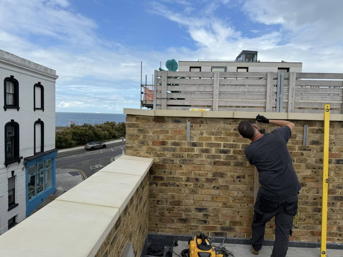 EV-ON engineer setting the K2 WallPV rail with a spirit level on the brick terrace wall overlooking Margate seafront, Kent.