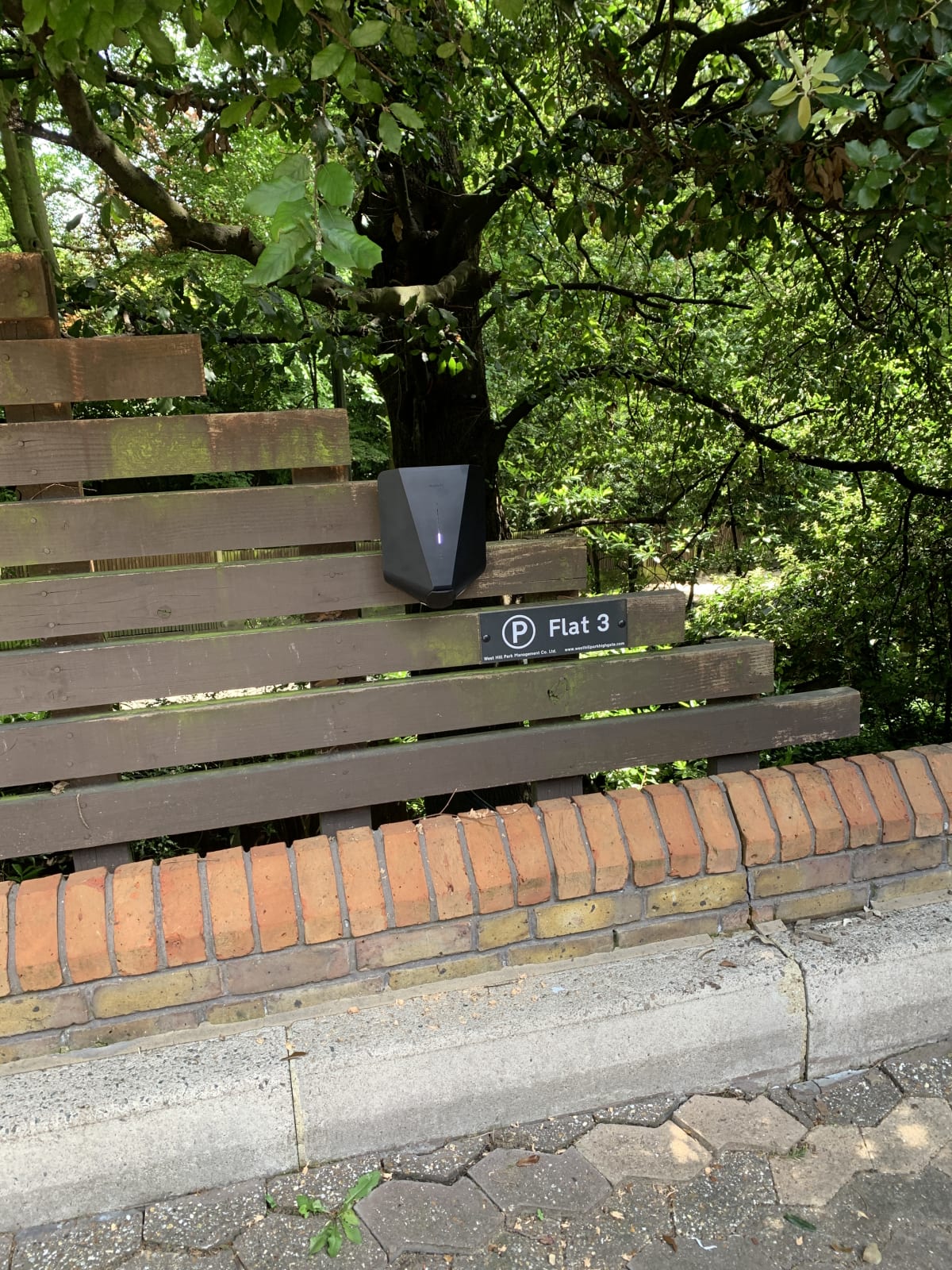 An Easee One EV charger mounted on a wooden fence at parking bay Flat 3 at Hill Court apartments in Highgate