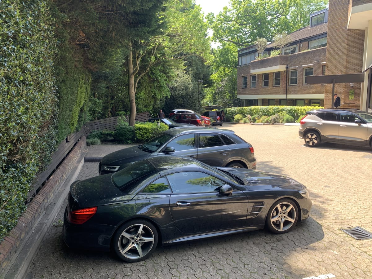 The landscaped car park at Hill Court residential apartments in Highgate showing mature trees and block paving