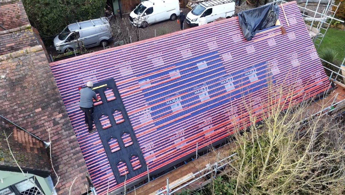 Aerial view of GSE in-roof mounting trays being laid across a traditional clay tile cottage roof in Broxted, Essex, with red roof battens visible.