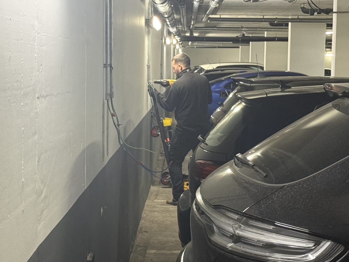 EV-ON engineer installing cable containment on the underground car park wall at The Avenue, Kilburn.