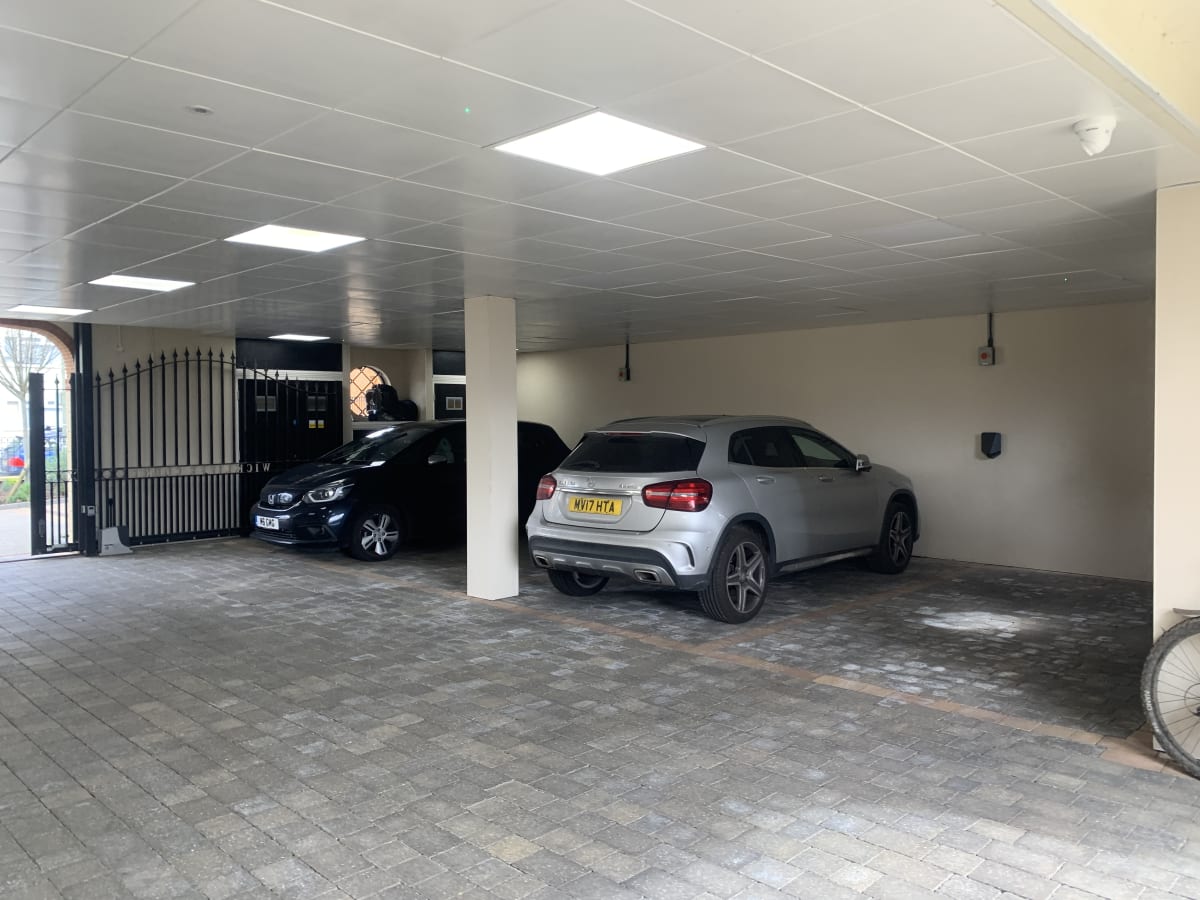 Interior view of a covered car park with block paved surface and vehicles parked at a residential complex in Hendon