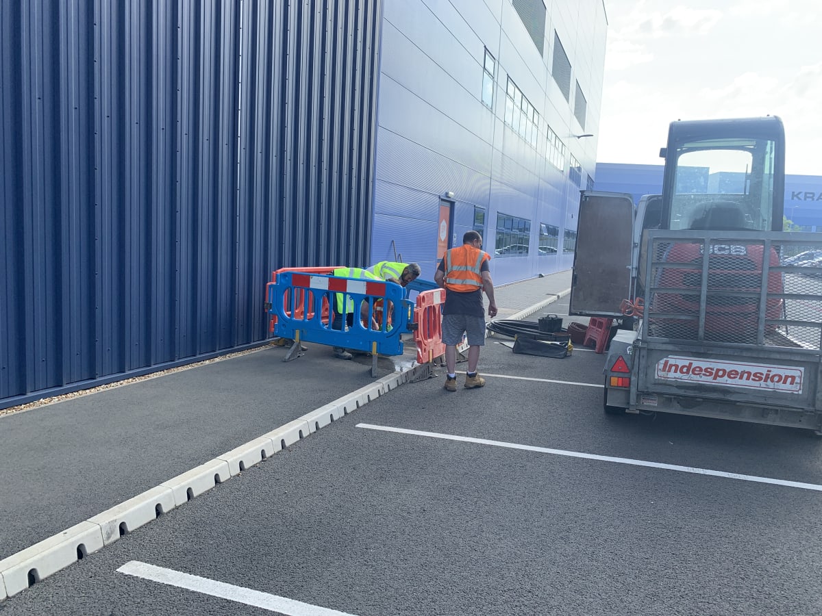 Workers excavating collapsed ducting in the car park during EV charger groundworks at Zeus Packaging, Biggleswade