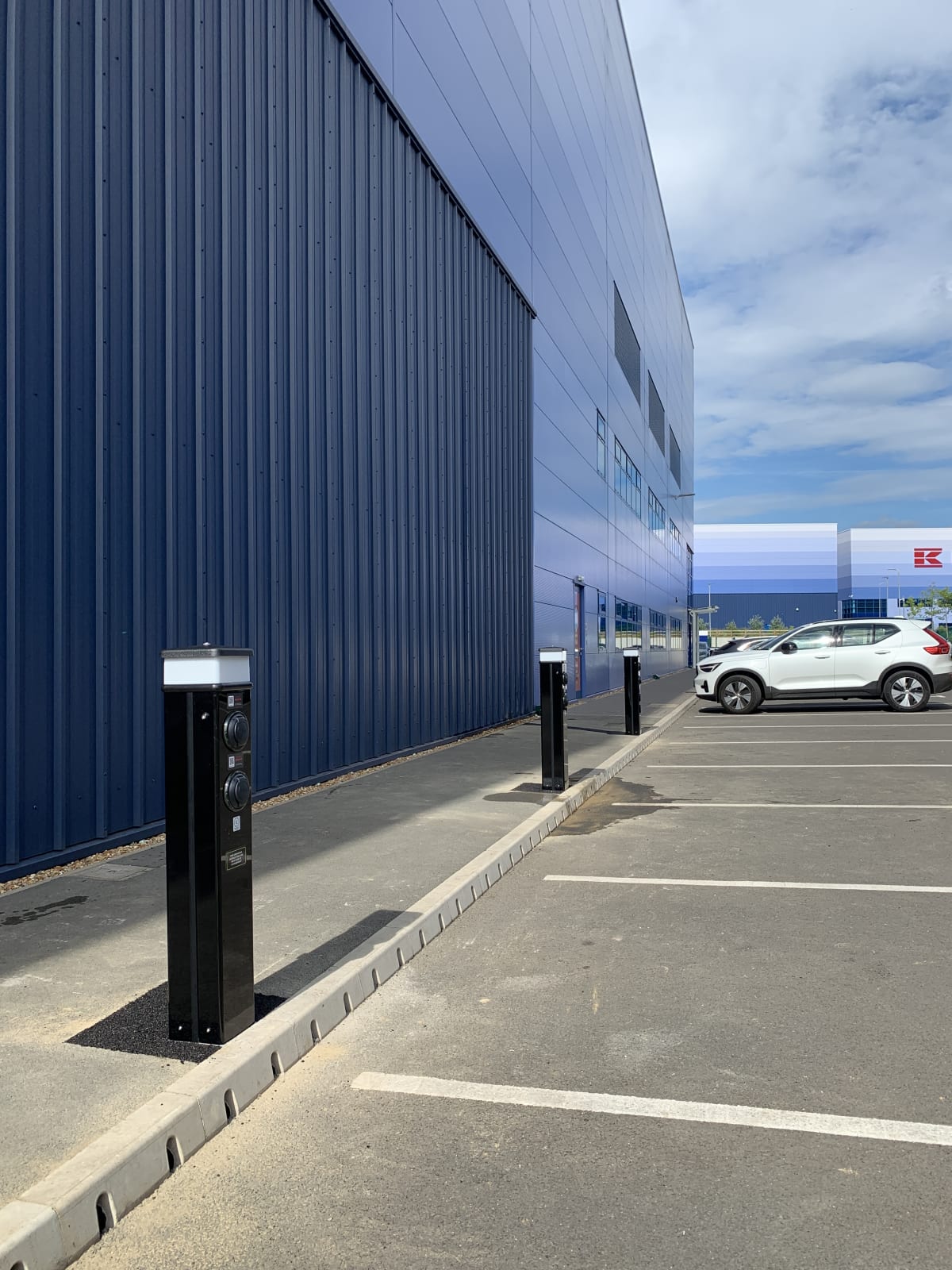 Row of Rolec EV charging pedestals installed along the Zeus Packaging warehouse wall at Stratton Business Park, Biggleswade