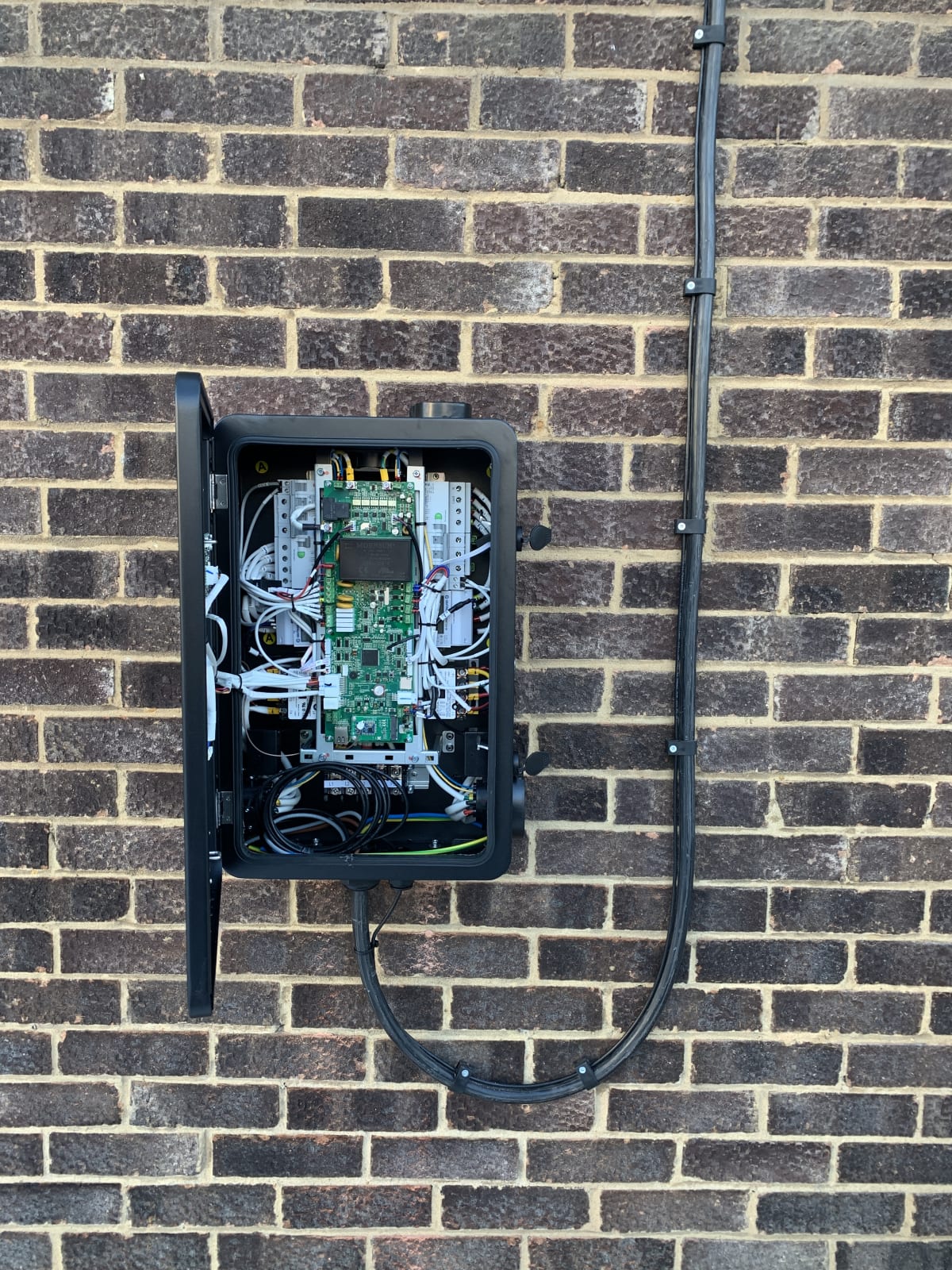 An EV charger enclosure opened to show the internal board and breakers during fault diagnosis
