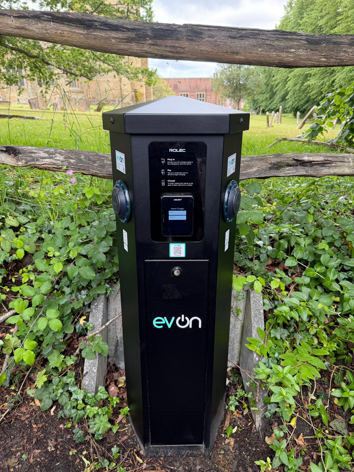 An evon branded Rolec charging pedestal in service beside a churchyard
