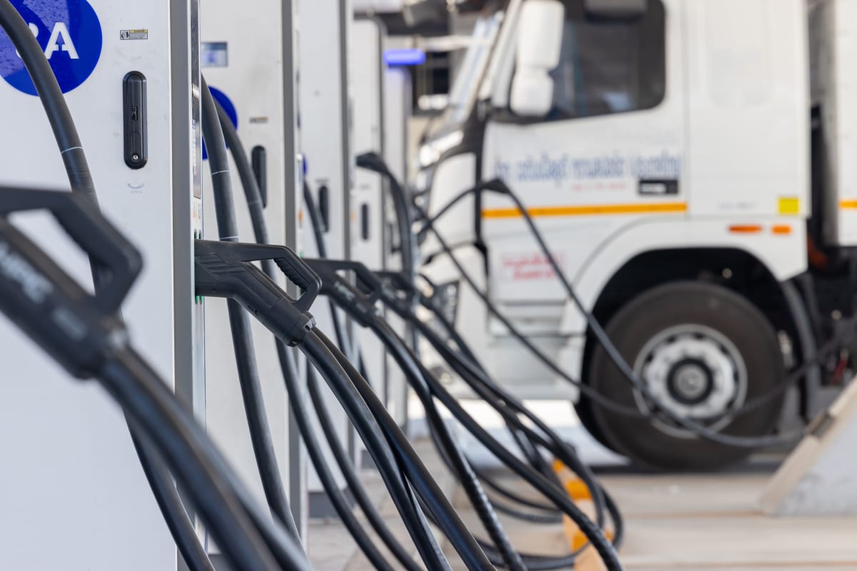 An electric truck charging at a bank of rapid chargers at a commercial fleet depot