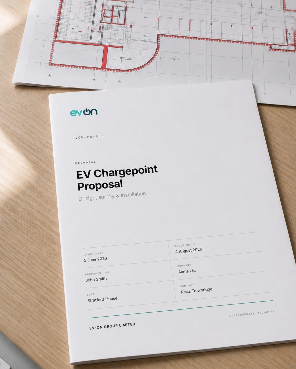 A printed evon EV chargepoint proposal document on a desk, laid over a car park layout drawing