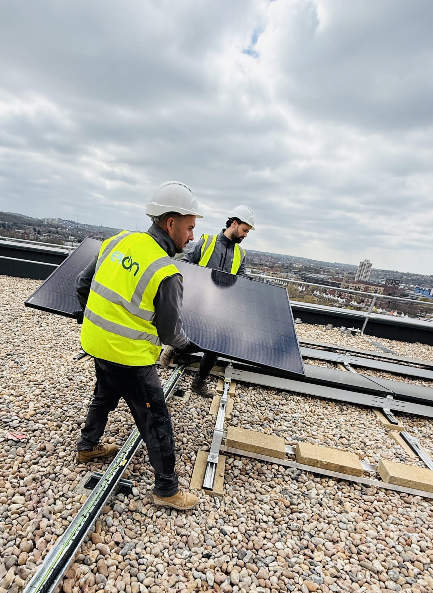 Two evon engineers in hi-viz installing a Jinko solar panel on a rooftop in Old Kent Road, London