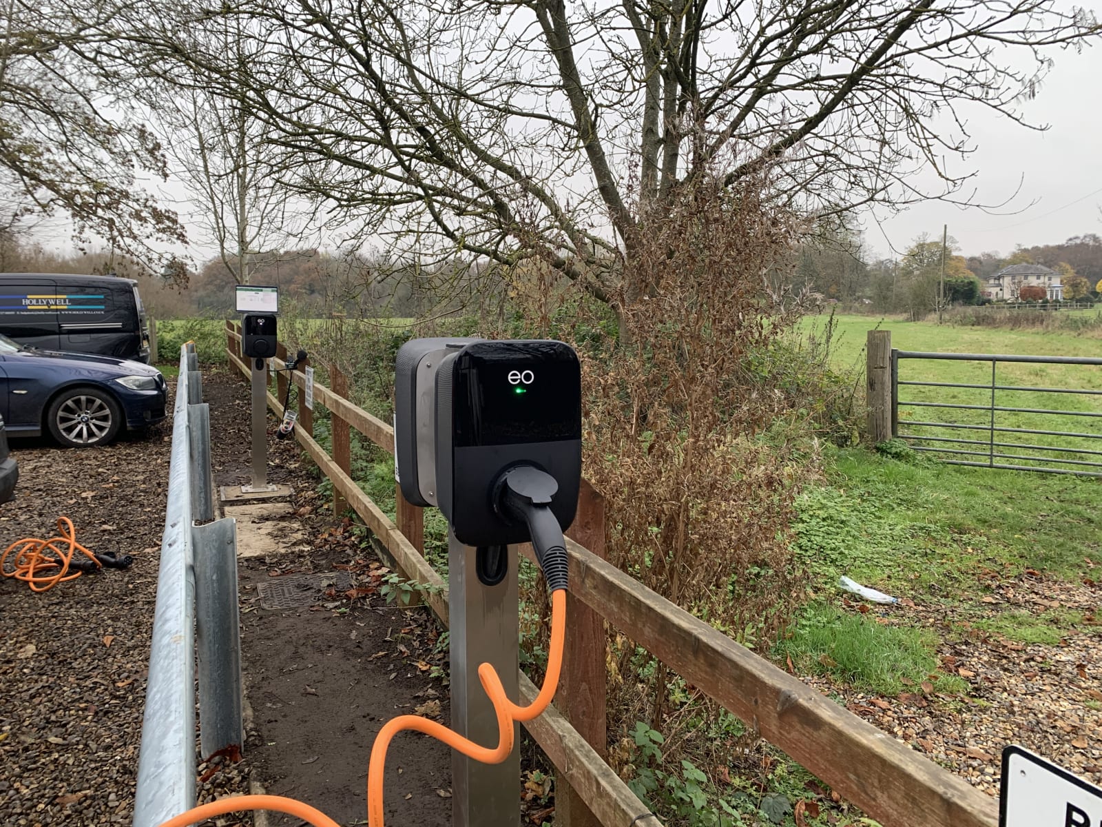An EO Genius 2 charger with green LED active on a metal pedestal in Hollywell's office car park in St Albans.