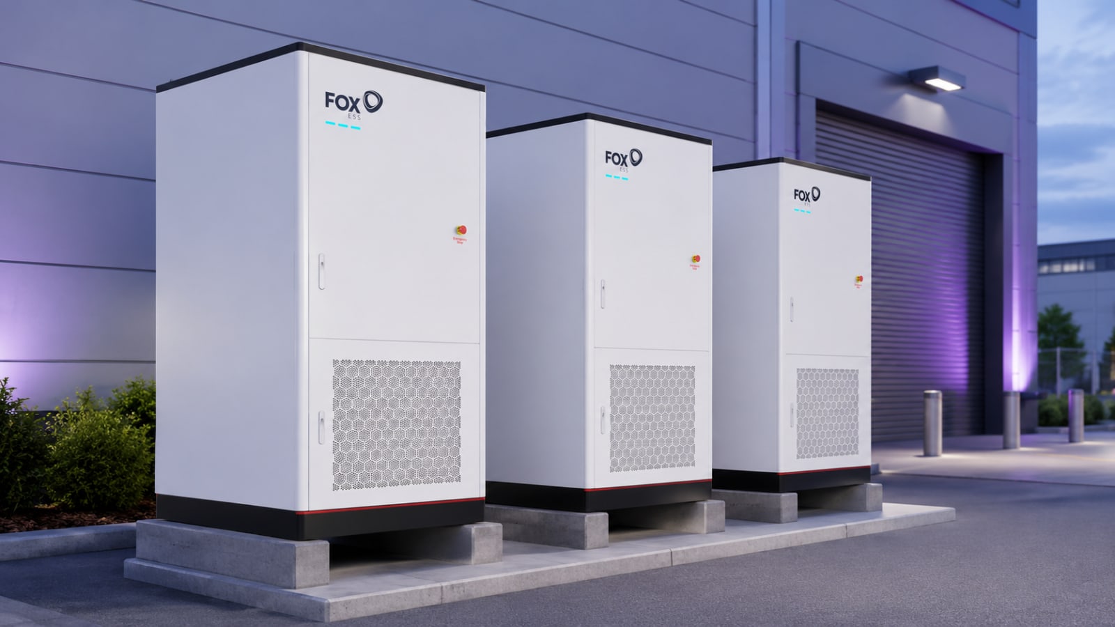 Three Fox ESS G-Max commercial battery storage cabinets outside an industrial unit at dusk.