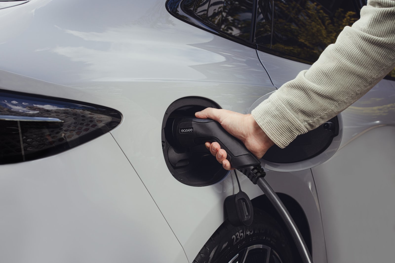 Plugging an EV charging cable into a white car at home