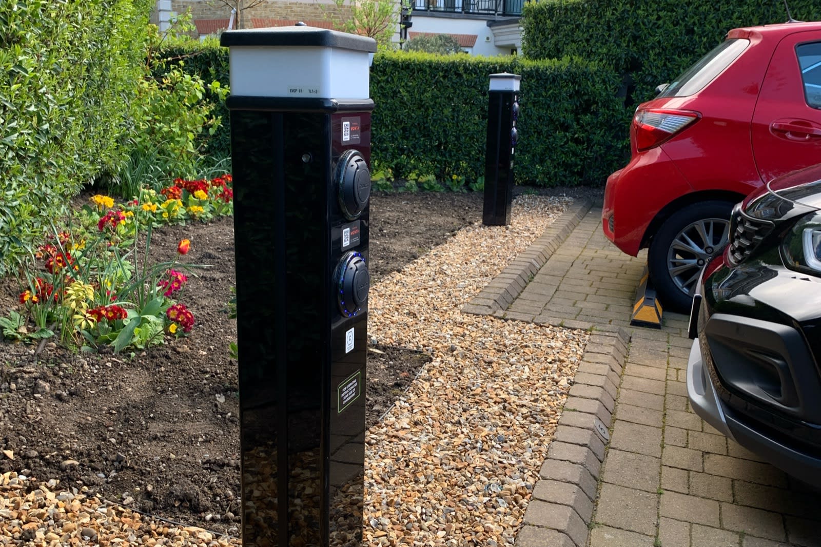 Two Rolec dual bollard EV chargers installed beside colourful flower beds and shingle landscaping at Ashby Lodge, Hendon.
