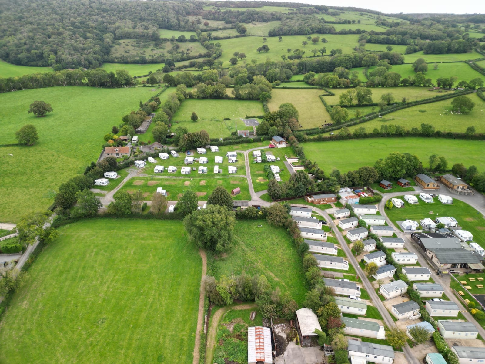 Aerial view of a UK caravan holiday park with touring and static caravans set among green countryside fields.
