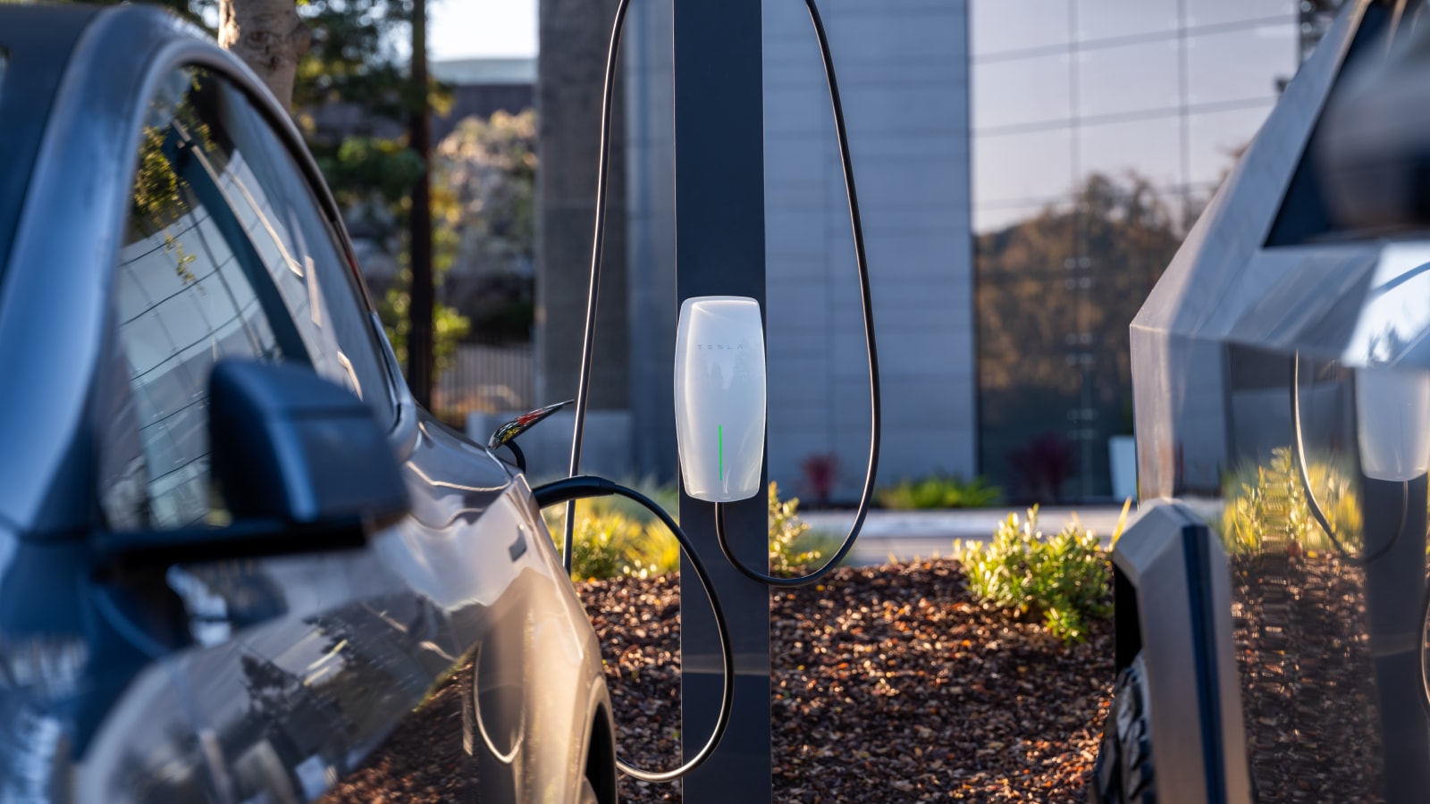Close up of a Tesla Destination Charging connector cable plugged into a car outside an office building.