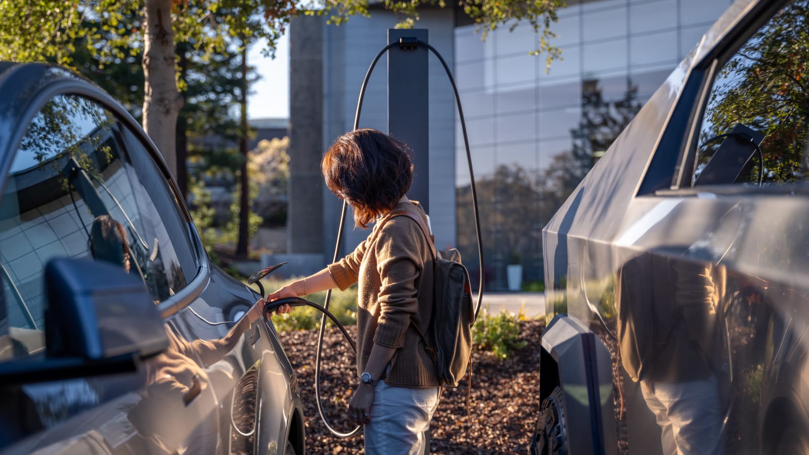 A guest walks toward a car connected to a Tesla Destination Charging point in a business car park.