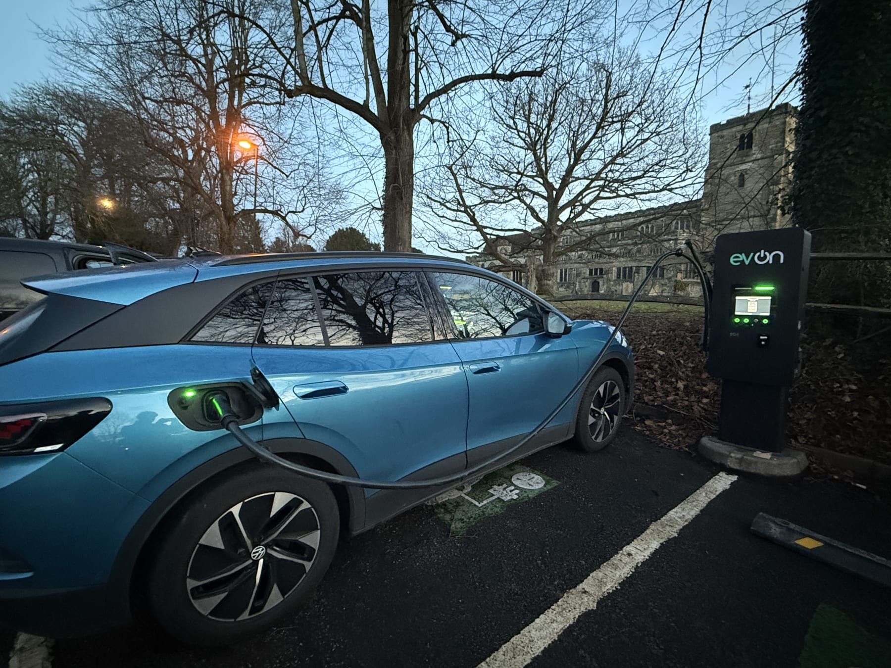 A Volkswagen ID electric car charging at an evon public charge point at dusk in Cranbrook, Kent