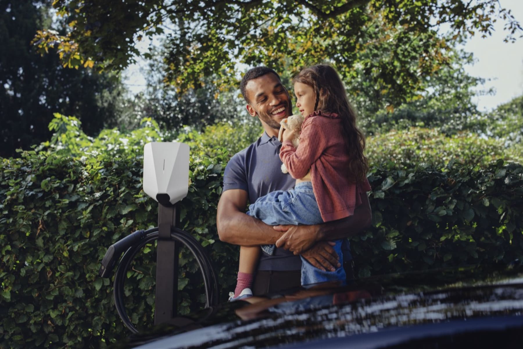 A father and daughter charging their electric car with an Easee charger at home